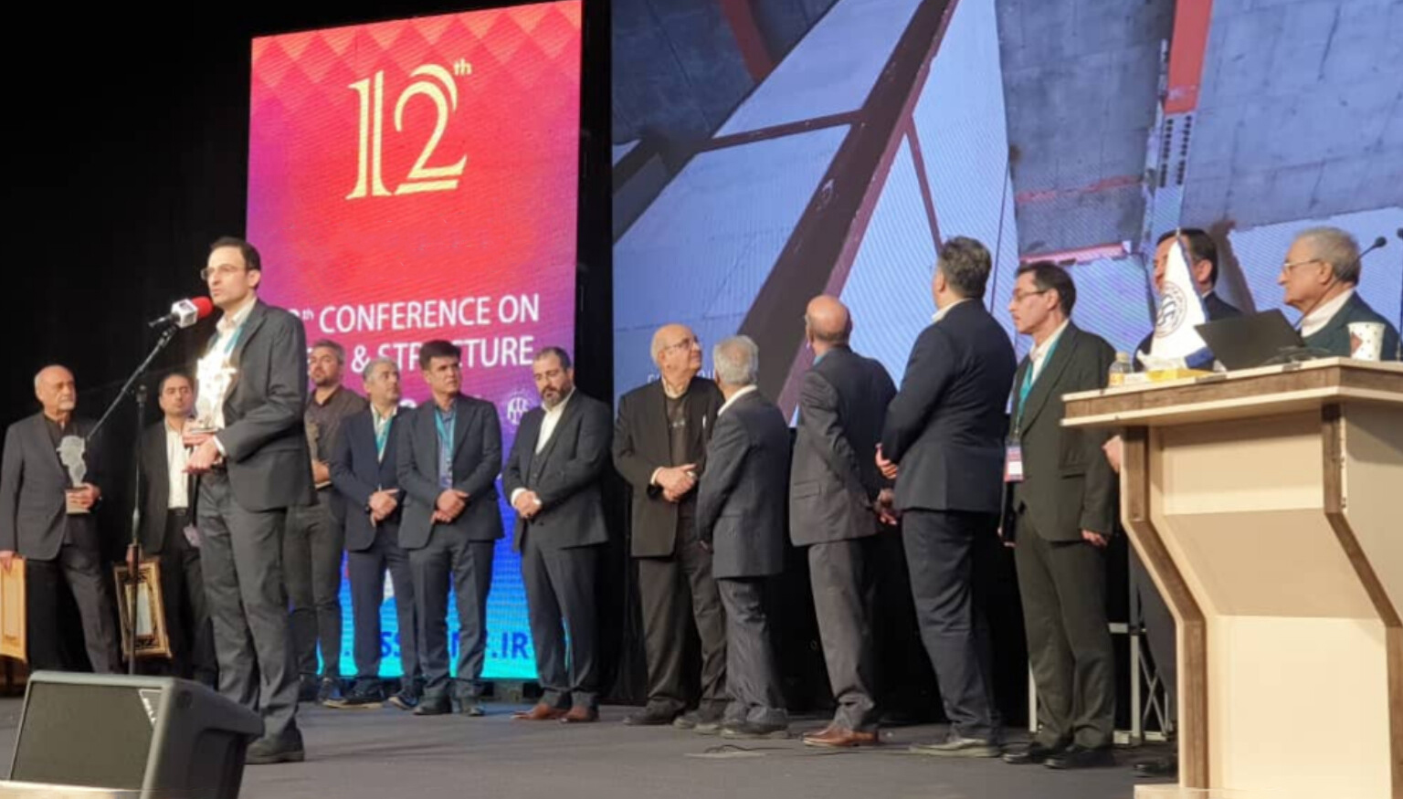 دکتر علی رضوی در حال سخنرانی در دوازدهمین کنفرانس بین‌المللی سازه های فولادی.